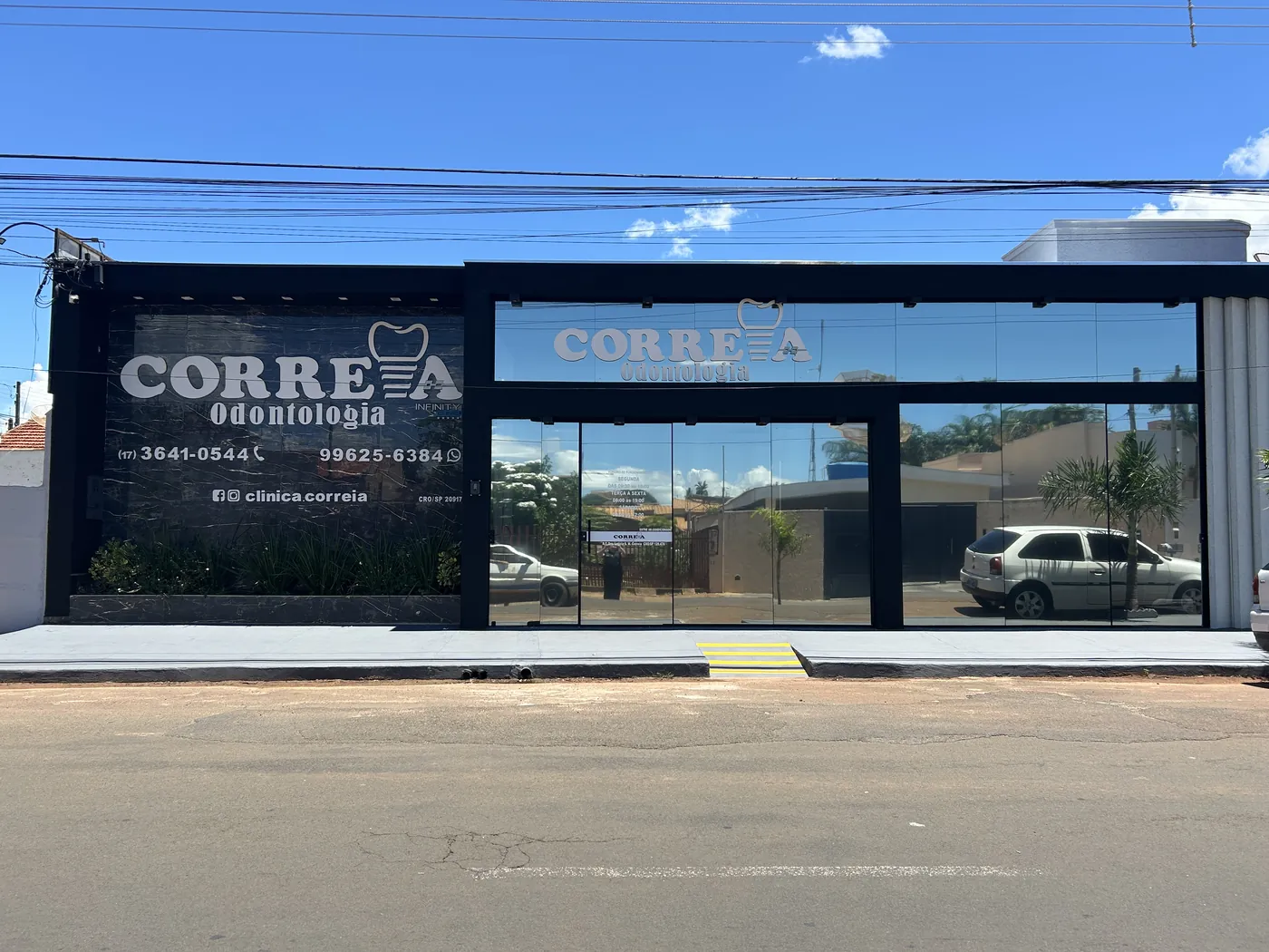 Fachada da unidade de Santa Fé do Sul: prédio de vidro escuro com o letreiro da Correia Odontologia e os telefones aplicados na vitrine